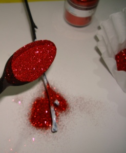 Spoon the glitter onto the glued branch.  Make sure to catch the excess in a coffee filter or on a piece of paper.